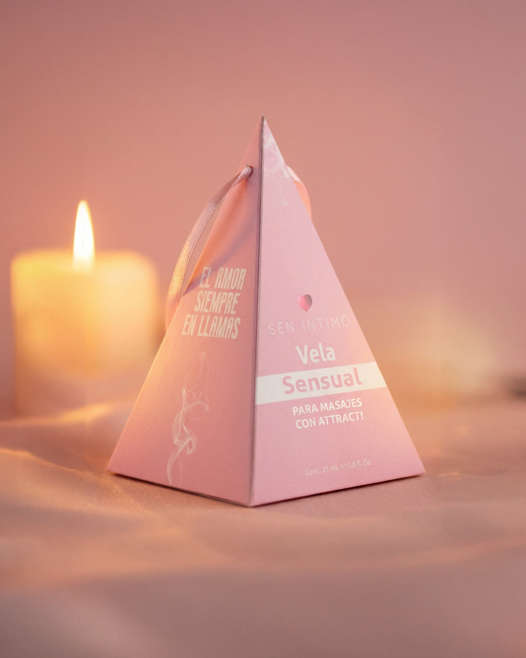 Vela Sensual para Masajes Sen Íntimo - caja pirámide rosa con vela encendida ambiente cálido romántico
